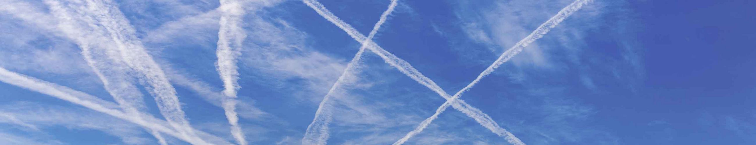 Verschiedene sich überschneidende Kondensstreifen von Flugzeugen sind am blauen Himmel zu sehen.