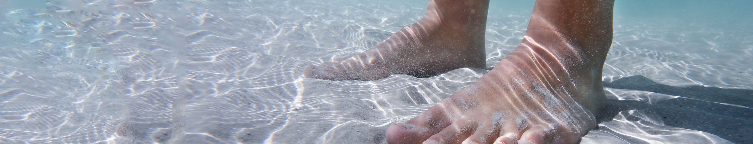 [Translate to English:] Füße unter Wasser auf Sand